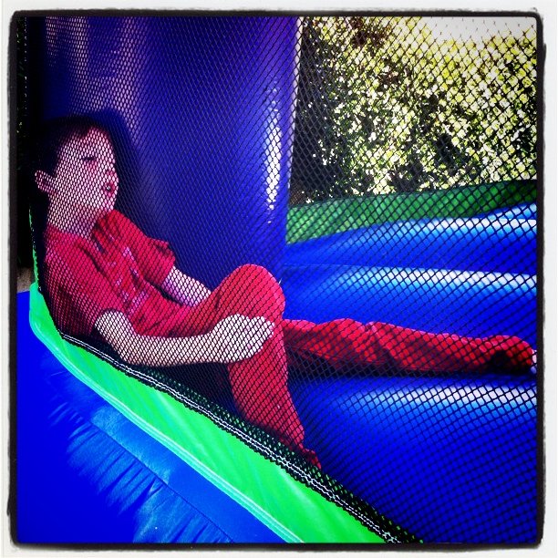 Leighton thru the netting of the bounce house. He likes red.  (Taken with instagram)